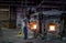 Worker scooping out melted glass in a kiln