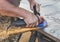 Worker scrapes welding welds off a metal workpiece with an angle grinder