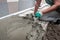 Worker screeding outdoor cement floor with screed
