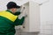 A worker screws a self-tapping screw into the wall of the upper kitchen cabinet