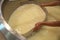 Worker separating curd from whey in tank at cheese factory