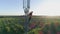 Worker serves cellular antenna with mobile phone in hand, aerial view of man in hard hat on background of city landscape