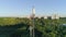 Worker servicing radio telecommunication tower with cell phone in hand in front of sunlight, drone view cellular antenna