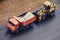 A worker with a shovel pours asphalt from a truck into the bucket of an excavator, top view