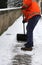 Worker while shoveling snow from frozen sidewalk