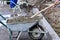 Worker shovels concrete from a wheelbarrow at curb block installation.