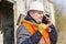 Worker with sledge hammer talking on cell phone