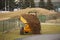 A worker on a small orange dump truck is transporting and emptying the ground forming the landscape at a sports stadium.