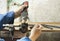 Worker with soldering iron for plastic pipes. Equipment for plumbing on wooden table on old wall background. Repairing