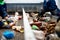 Worker sorts trash on conveyor belt at waste recycling plant