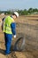 A worker in a special vest at a construction site takes a bundle of wire for work with the foundation