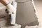 Worker spreading concrete on ceramic tile with spatula, closeup