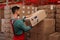 Worker stacking cardboard boxes with shipping icons in warehouse. Wholesaling