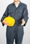 Worker standing in blue coverall holding hardhat