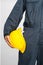 Worker standing in blue coverall holding hardhat