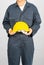 Worker standing in blue coverall holding hardhat