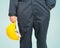 Worker standing in blue coverall holding yellow hardhat