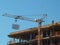 A worker standing on the building construction controls the lifting of the load crane