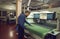 Worker standing near cutting machine in workshop of footwear manufacturing factory