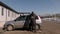 Worker takes large cardboard box out of car near building