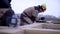 Worker takes notes on measurements of wooden board. Clip. Worker in form of helmet records measurements on wooden board