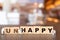 Worker team on Unhappy word in wooden alphabet letters with prefix un crossed out, leaving the word Happy