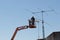 Worker on telescopic elevator repairing a antenna. Copy space