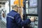 Worker touching the switch button on the board of computer numerical control of the lathe