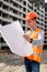 worker in uniform and a helmet holds in his hands a detailed plan on the construction site.