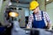 Worker in uniform operating in manual lathe in metal industry factory.