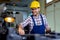 Worker in uniform operating in manual lathe in metal industry factory.