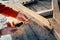 Worker up wooden rail with a with a screwdriver, on table in sawdust