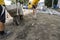 Worker used wheelbarrow for transporting sand to another man with a shovel for construction of sidewalk road