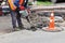 A worker uses an electric jackhammer to loosen old asphalt while repairing a road