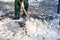 A worker uses a metal spade to break frozen pieces of ice off the pavement