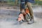 A worker uses a portable chainsaw and a diamond cutting disc to cut old asphalt on the road