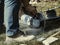 worker uses a stone cutter to cut the brick pavers