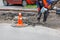 A worker using an electric jackhammer and a gasoline generator cleans the area near the sewer manholes from the old asphalt