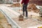 Worker using pavement slabs and shovel to build stone sidewalk. Close up of construction worker installing and laying pavement sto