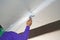 Worker using plaster gypsum on putty knife at ceiling