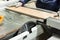 Worker using saw machine to make furniture at carpenters workshop.