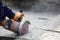 Worker using tool to cut concrete floor with blank space on right