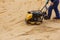 Worker using vibratory plate compactor for compaction sand during path construction.