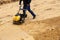 Worker using vibratory plate compactor for compaction sand during path construction.