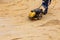 Worker using vibratory plate compactor for compaction sand during path construction.