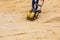 Worker using vibratory plate compactor for compaction sand during path construction.