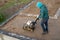 A worker with a vibrating tamping machine rams the ground