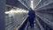 A worker is walking along the corridor of a poultry-house and observing little chickens