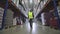 A worker walks through a factory warehouse. A man walks through the warehouse view from the back slowmotion.Rear view of