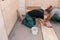 The worker washes freshly laid tiles on the bathroom floor with cement glue